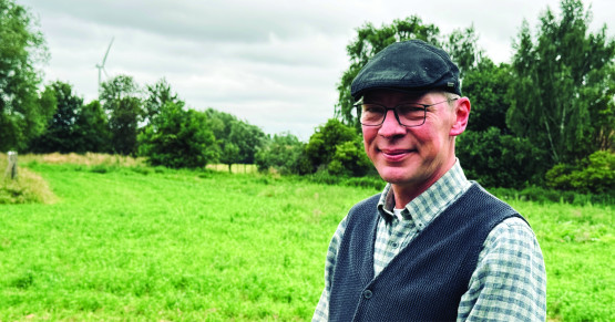 Ingo Sander steht auf einer grünen Wiese und schaut freundlich in die Kamera.